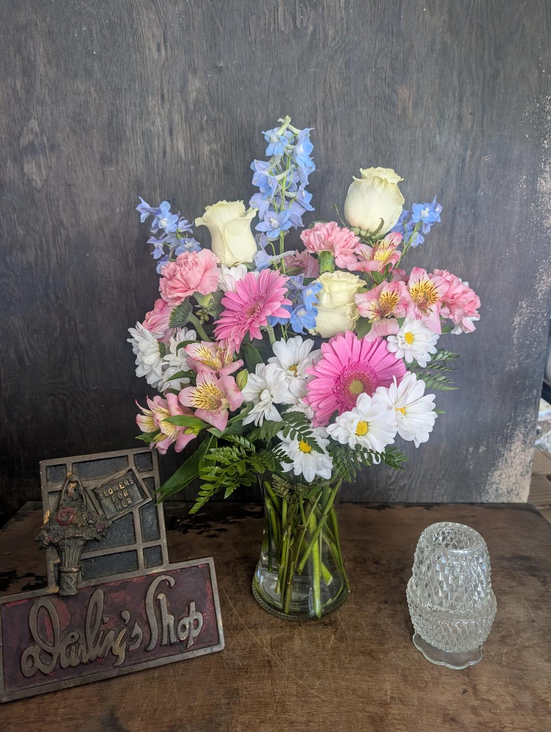 Mixed bouquet in a clear glass vase with pink, white, and blue flowers