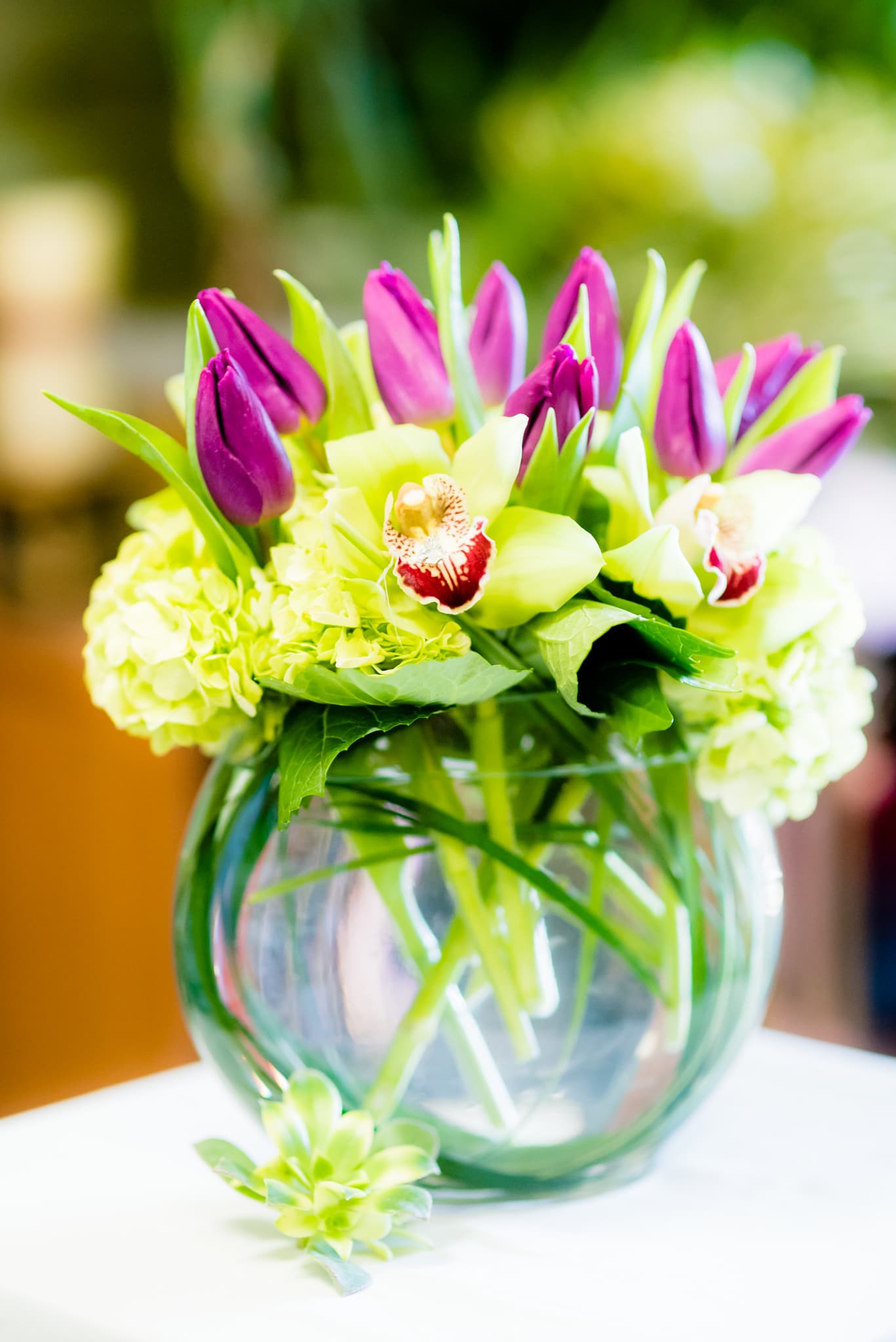 Bouquet of purple tulips and pale green orchids in a glass vase