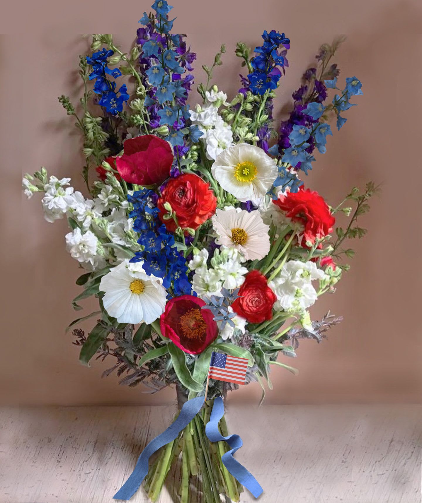 Red White &amp; Blue bouquet - Red, White and Blues in a pretty and symbolic hand tied bouquet of seasonal flowers with a very natural and wild look like blue delphinium, white poppies/cosmos, red ranunculus and peonies. A small American flag is attached.   We offer a personal hand delivery by our own delivery staff and guarantee the flowers will look perfect, when they arrive. 