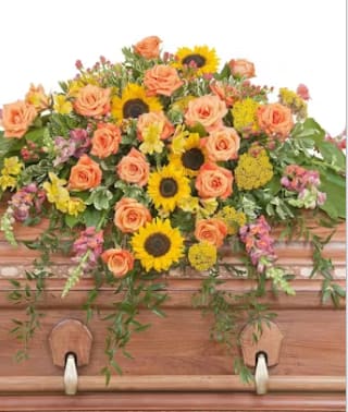 HEAVEN'S SUNSET CASKET SPRAY - The colors of sunset are evident in this beautiful spray of Sunflowers and Roses with accents of other premium flowers and foliage.  