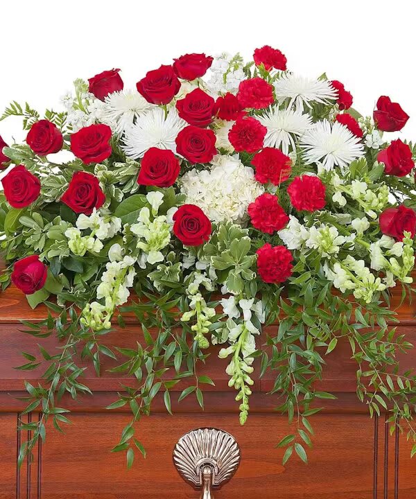 ENDURING STRENGTH CASKET SPRAY - Red and white premium varieties of flowers combine with lush foliage to make this casket spray impression of enduring strength.  