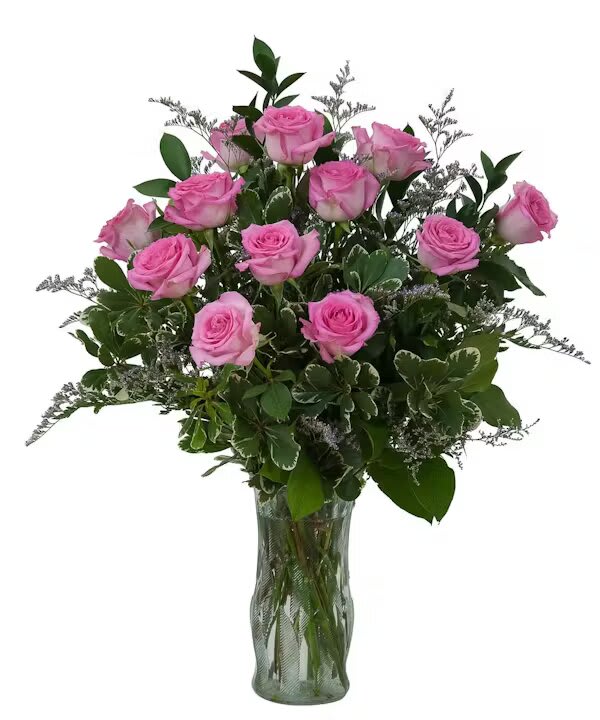 Pink roses arranged in a clear glass vase with greenery