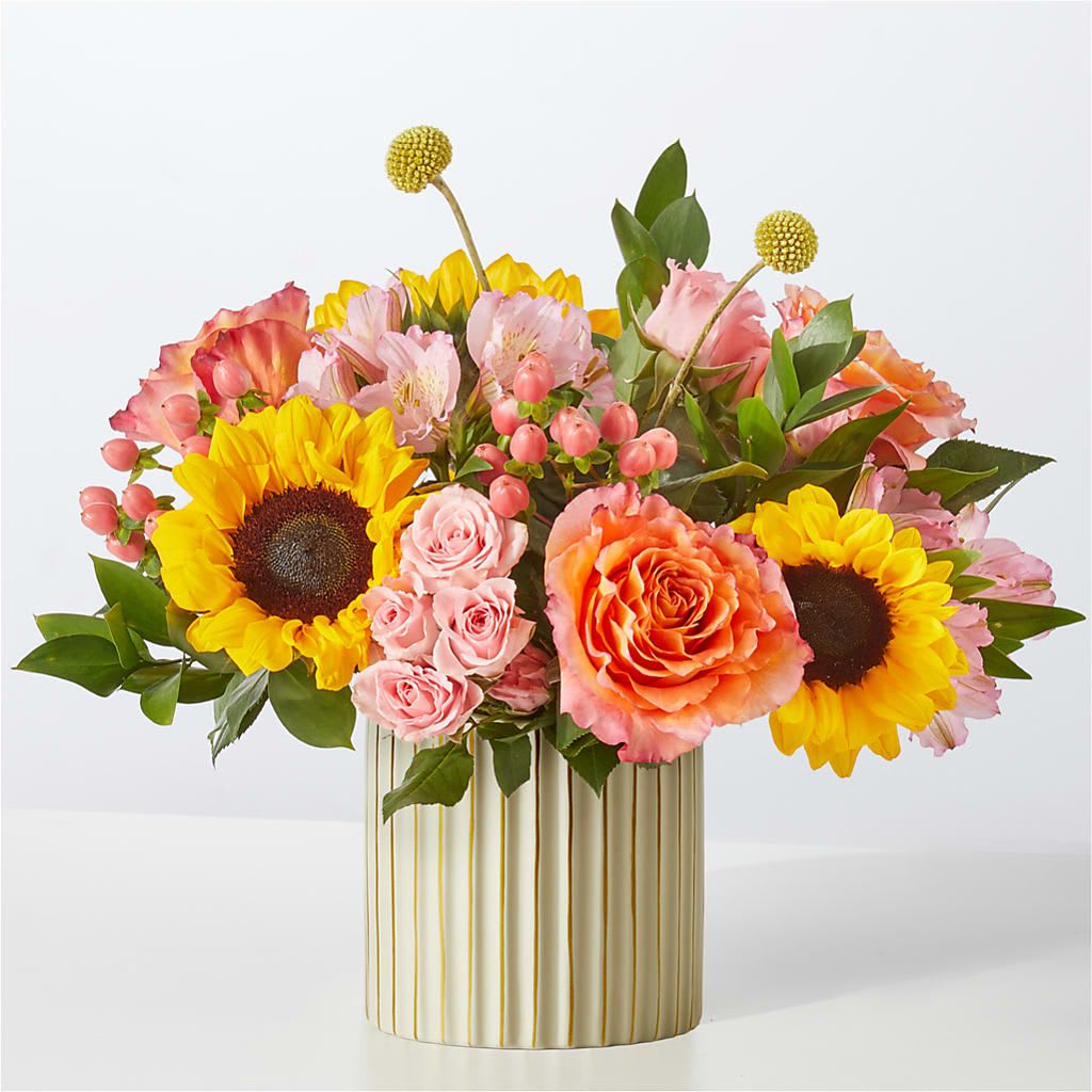 Sun's Out Bouquet - A combination as sweet as citrus, these peach, orange and yellow blooms shine to make this day a colorful one!  3 Orange 50 cm Roses 3 Yellow Sunflowers 2 Pink Spray Rose stems 2 Pink Hypericum Berry stems 2 Pink Alstroemeria stems 2 Yellow Craspedia stems 3 Israeli Ruscus stems 
