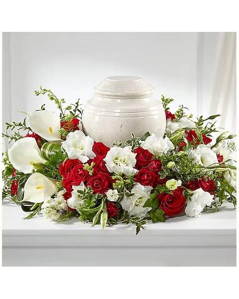 Red roses and white calla lilies arranged around a white urn