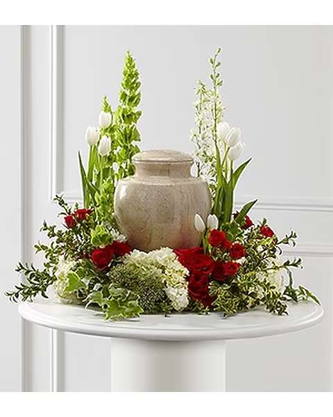 Red roses and white tulips arranged around a beige urn