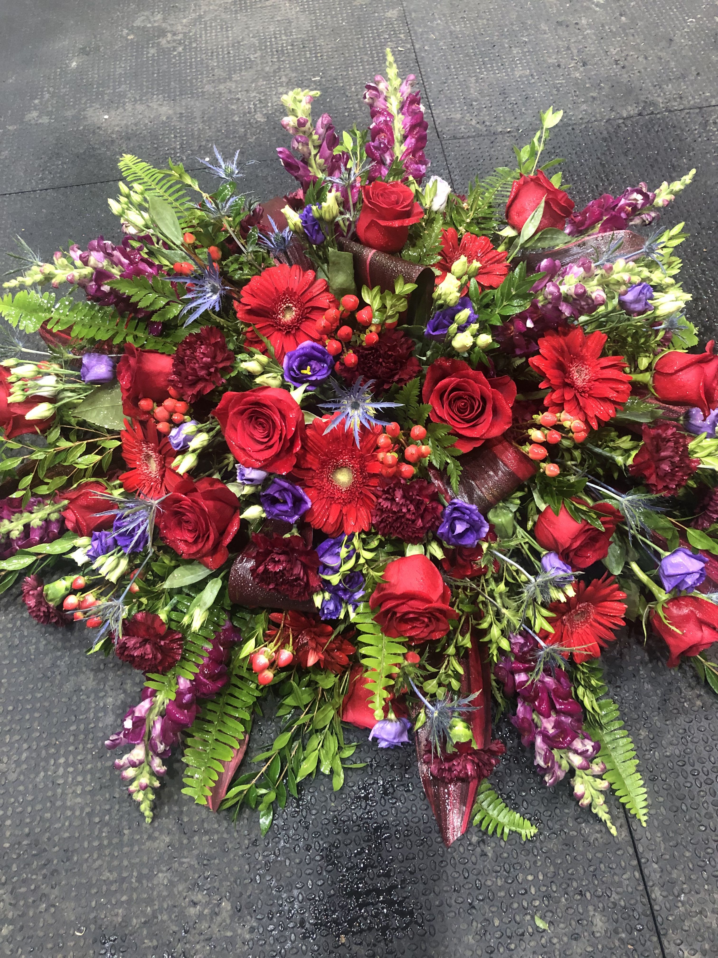 LOVING REMINDERS - A stunning funeral piece with deep reds and purples to remind those of the memories of passed loved ones