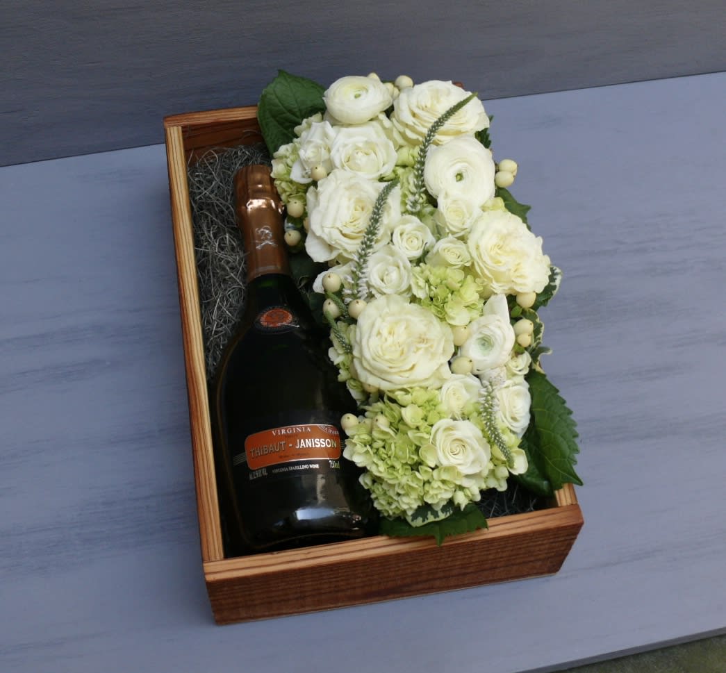 Blanc De Chardonnay Gift Box - A beautiful wooden gift box, locally hand-crafted from reclaimed wood. A 750ml bottle of Thibaut-Janisson's rich yet dry Blanc De Chardonnay rests on a bed of Spanish moss, alongside a beautiful bed of flowers in the pavé style.  You may specify a color for this arrangement if desired.   Wine Description: This is a truly historic offering, putting Virginia in conversation with the great wines of France’s champagne region. Made from 100% chardonnay grapes, this wine manages to be rich and dry at the same time. This is a bottle made for every kind of celebration. Bubbles go with everything!  Before placing your order, please ensure that the recipient is above 21 years of age and will be home to receive the delivery, as ABC regulation requires that we check photo ID upon delivery.  If no one is present at the delivery site, delivery cannot be completed.  Box measures 8.5x11.5".