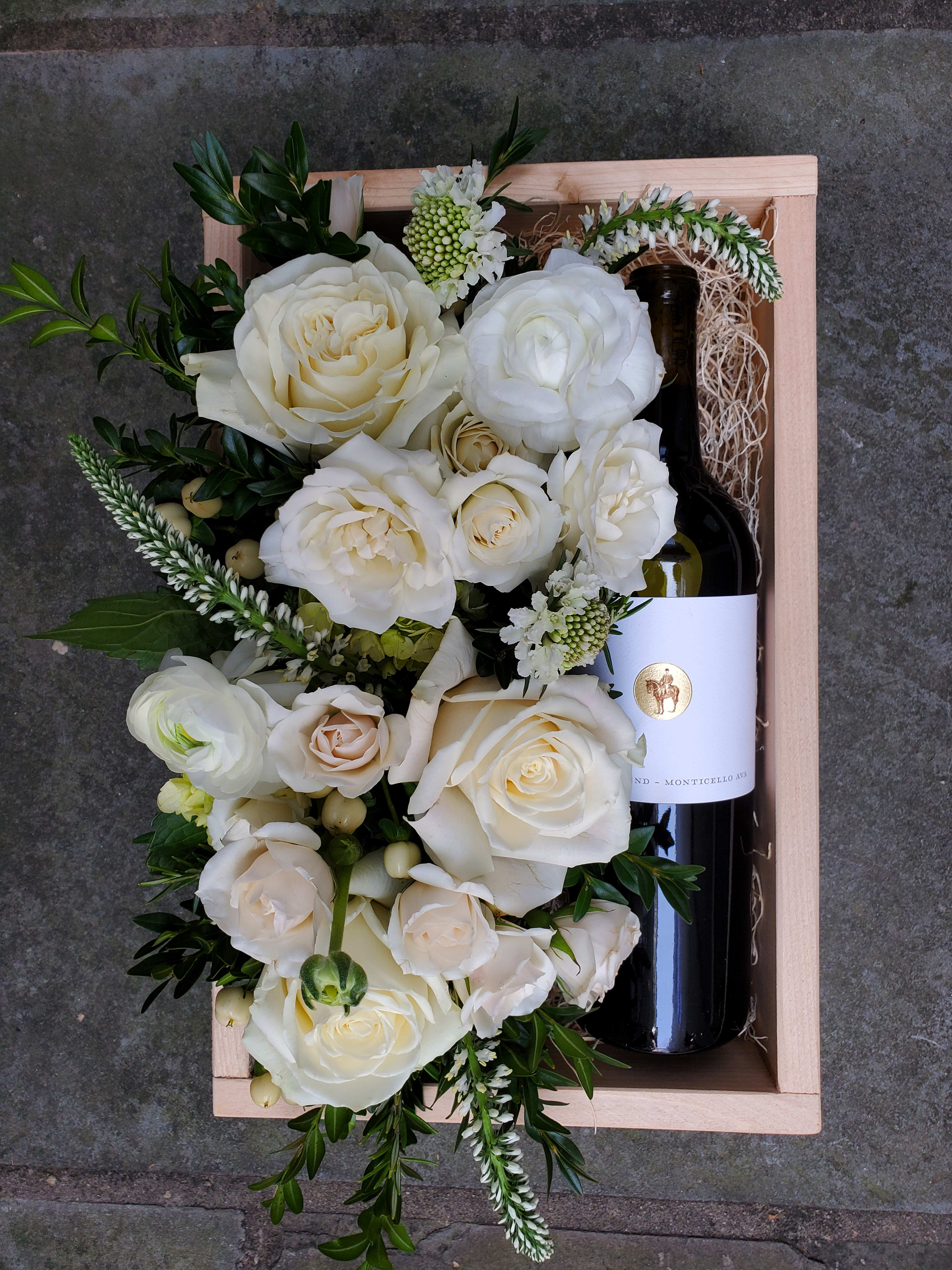Estate Red Wine Gift Box - A beautiful wooden gift box, locally hand-crafted from reclaimed wood. A bottle of Southwest Mountains Vineyards' Estate Red wine rests on a bed of Spanish moss, alongside a beautiful bed of flowers in the pavé style. You may specify a color for this arrangement if desired.  Wine Description: This Estate Red is a warm blend of Southwest Mountains Vineyards' Cabernet Franc, Petit Verdot and Merlot -- boasting a bouquet of stonefruit like cherry and plum, with hints of tobacco leaf and a sweet mocha finish.  Before placing your order, please ensure that the recipient is above 21 years of age and will be home to receive the delivery, as ABC regulation requires that we check photo ID upon delivery. If no one is present at the delivery site, delivery cannot be completed.  Box measures 8.5x11.5".