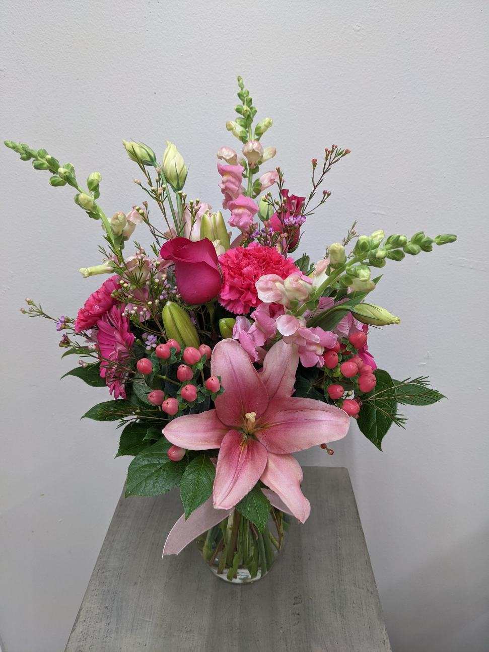 Pink lily and mixed flower bouquet in a clear glass vase