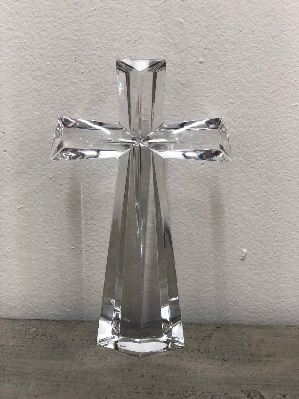Clear glass cross figurine on a plain surface