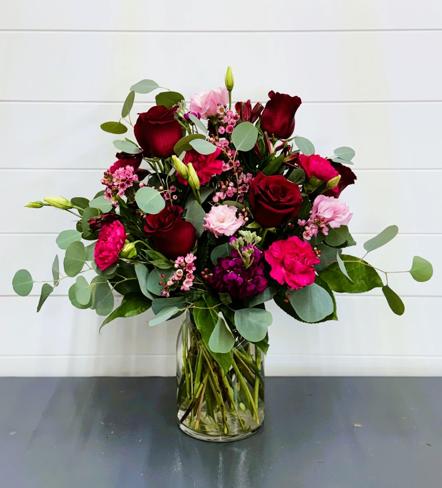 Bouquet of red roses and pink flowers in a clear glass vase