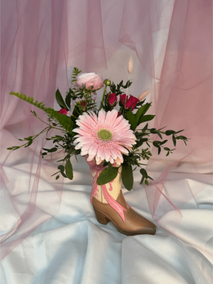 Western Romance - Fall head over boots with Western Romance, a romantic Western-inspired floral arrangement featuring a soft pink gerbera daisy, roses, and fresh greenery designed in a charming cowboy boot keepsake vase. Perfect for Valentine’s Day, anniversaries, or sweeping a country sweetheart off their feet, this playful yet heartfelt arrangement blends rustic charm with true romance.
