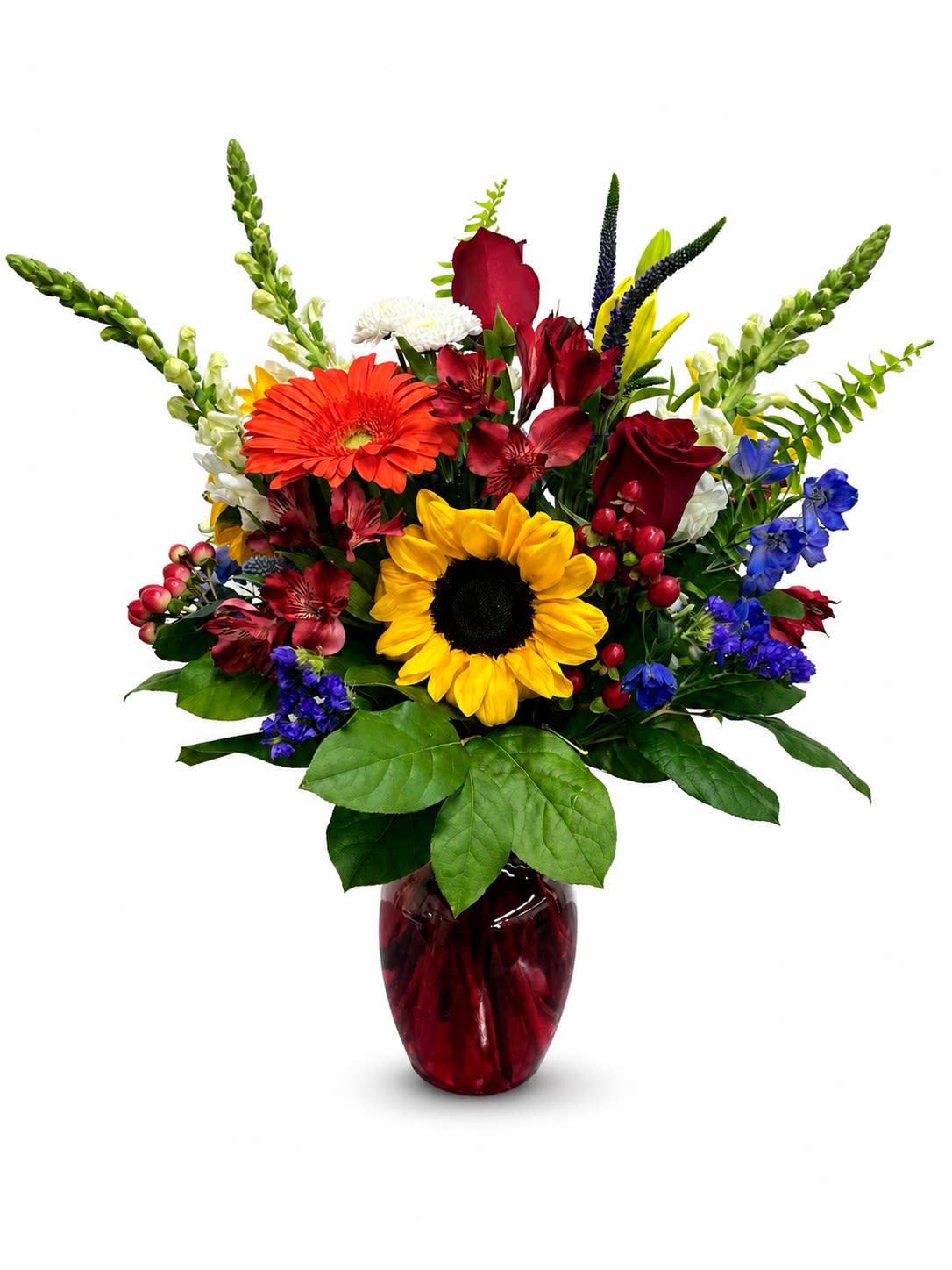 Ruby And Sunshine  - Bring warmth, color, and garden-inspired beauty to any occasion with Ruby &amp; Sunshine. This radiant floral design features cheerful sunflowers, elegant roses, and a vibrant mix of blooms including gerbera daisy, alstroemeria, hypericum berries, blue delphinium, snapdragons, and veronica, beautifully complemented by lush assorted greenery.  Designed with golden sunshine tones and rich ruby accents, this arrangement creates a joyful, eye-catching display that feels fresh, elegant, and full of life. Perfect for birthdays, celebrations, thank-you gifts, or adding a bright touch of beauty to any space.  Local flower delivery available throughout Smyrna, Austell, Mableton, Marietta, Powder Springs, and Atlanta, GA.