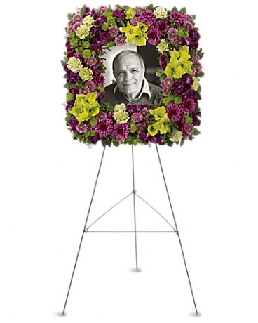 Floral funeral easel wreath framing a black-and-white portrait