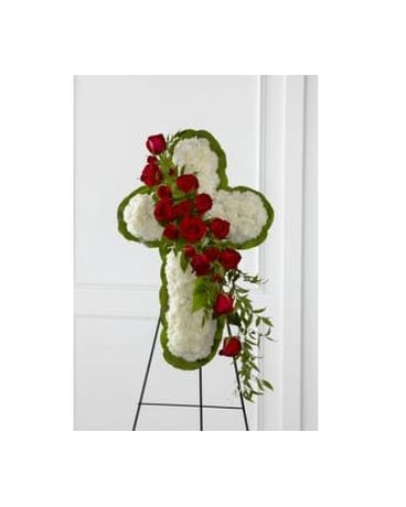 Cross-shaped floral tribute with red roses and white flowers on an easel
