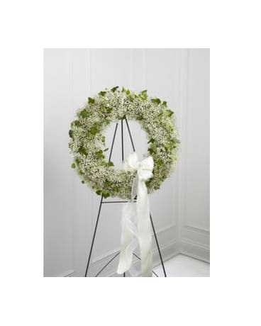 White floral wreath on a black stand with a white ribbon bow