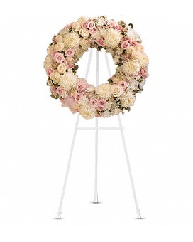 Round floral wreath of pale pink and cream flowers on a stand