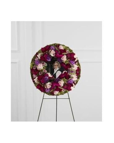 Circular floral wreath on an easel with a photo in the center