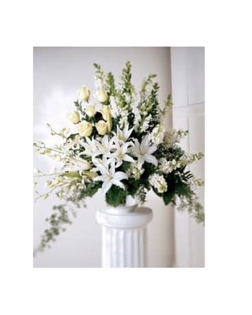 White floral arrangement in a pedestal vase with lilies and roses