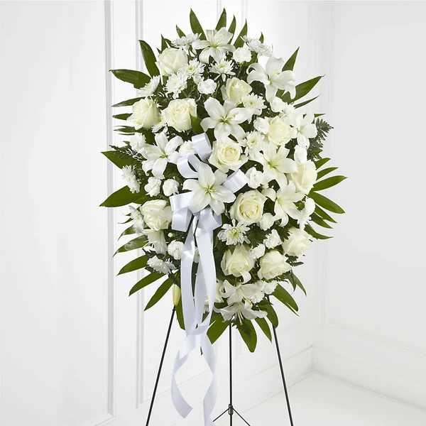 White floral standing spray with roses and lilies on an easel