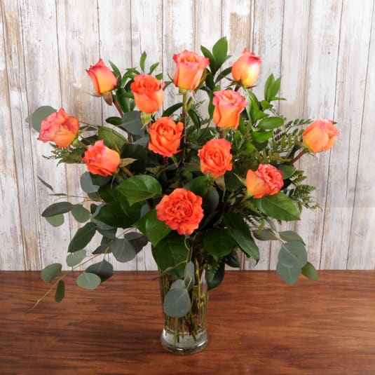 Tall arrangement of orange roses in a clear glass vase