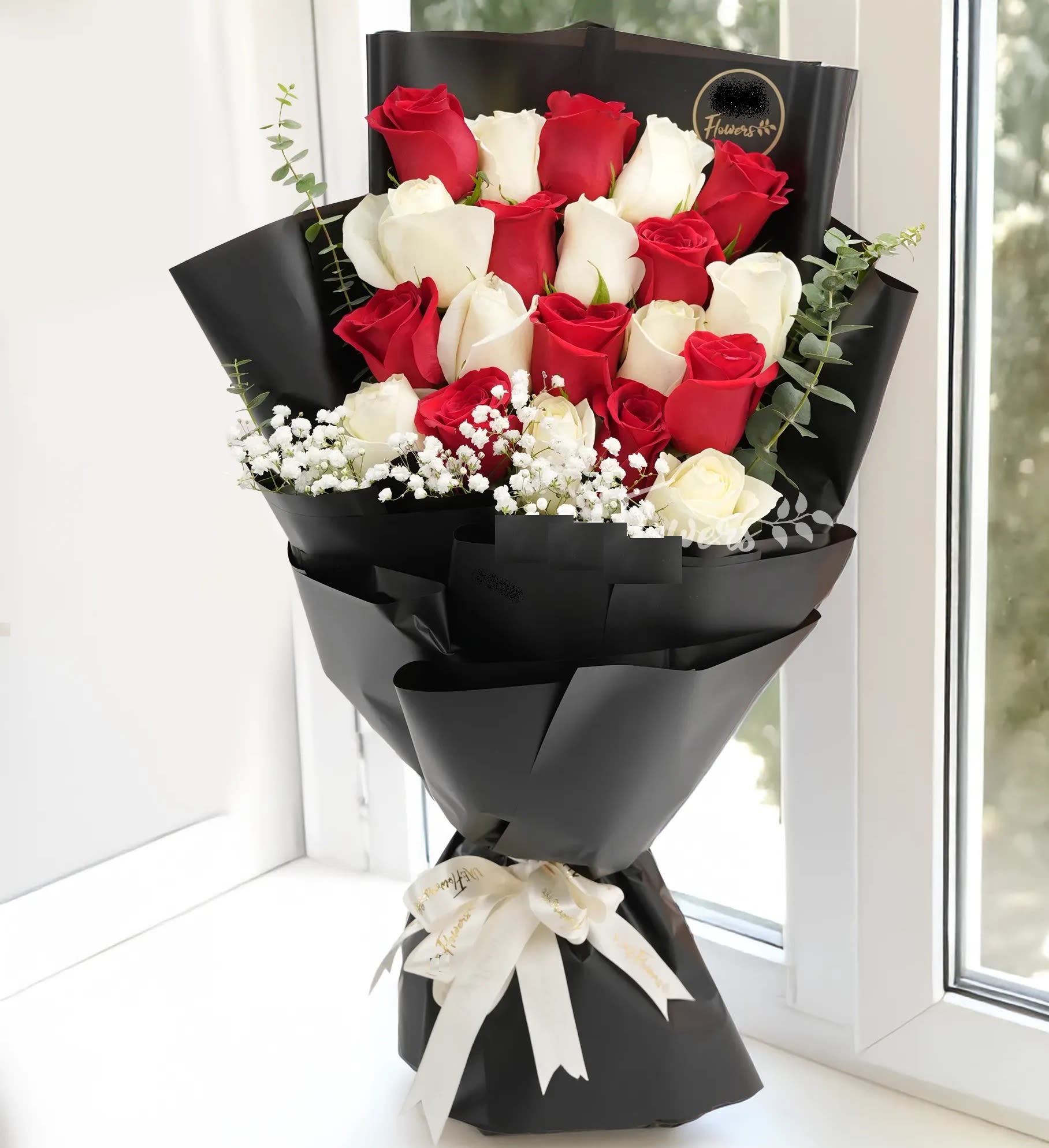 Bouquet of red and white roses wrapped in black paper with a white ribbon
