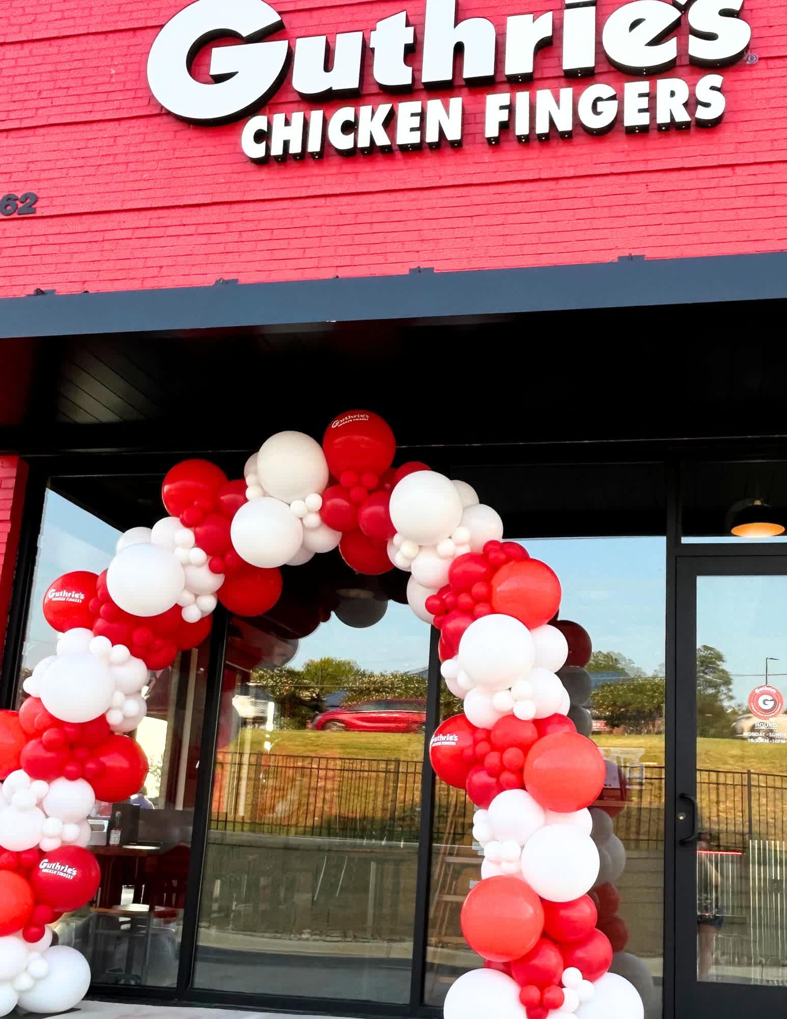 Red and white balloon arch outside a Guthrie's Chicken Fingers storefront