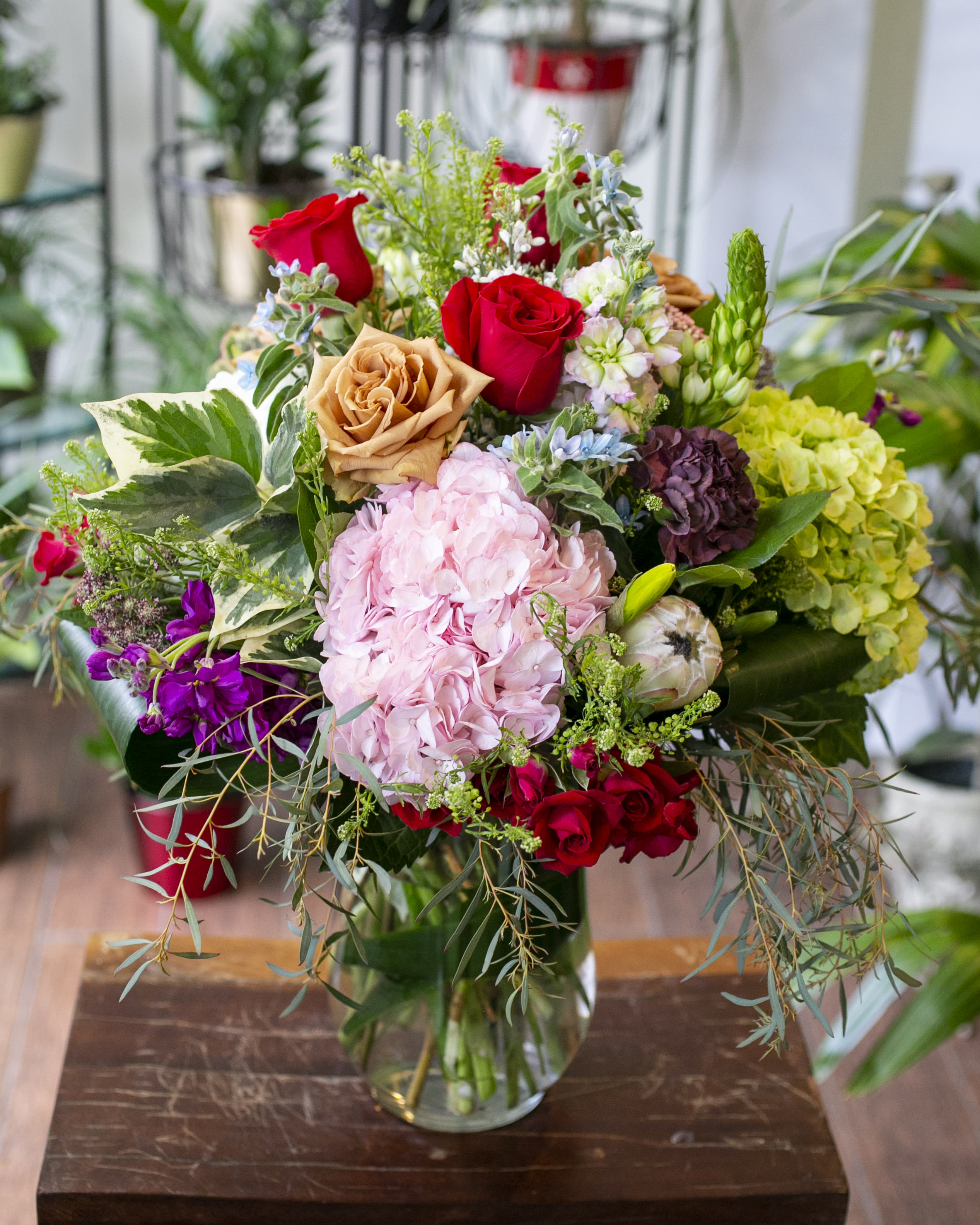 Mixed bouquet of roses, hydrangeas, and assorted blooms in a glass vase