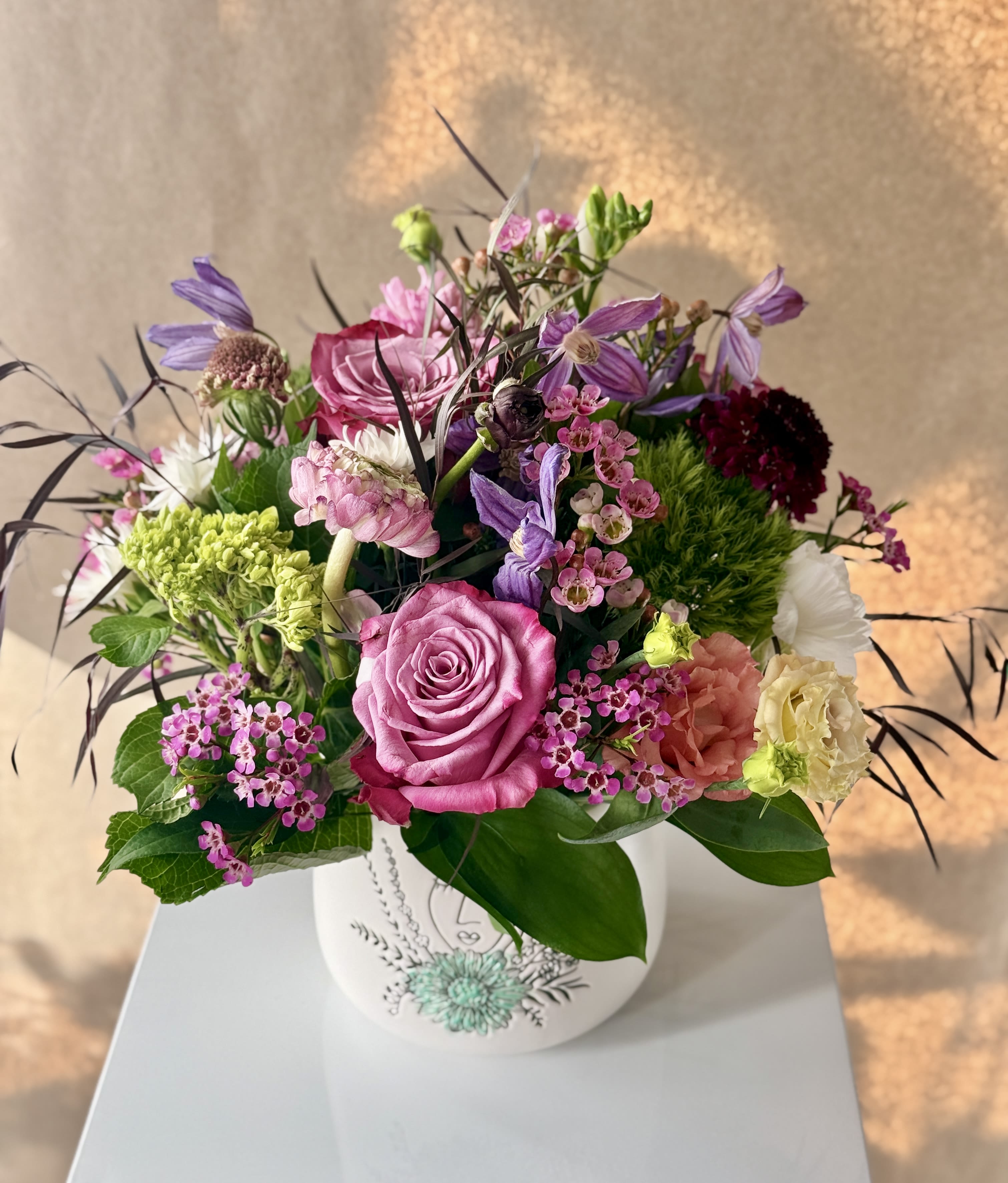 Pink and purple mixed flower arrangement in a white vase