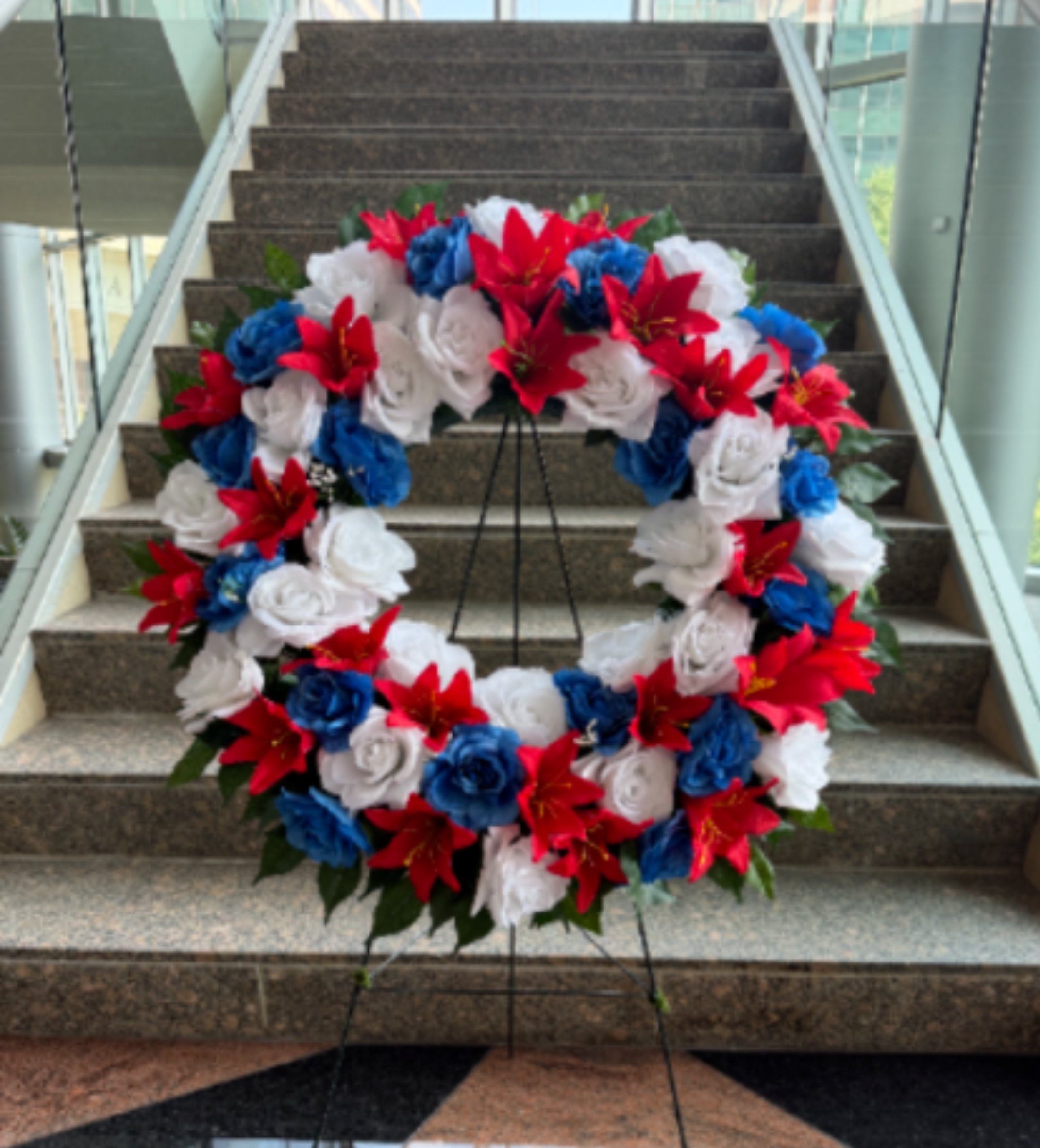 Large red, white, and blue floral wreath on a stand