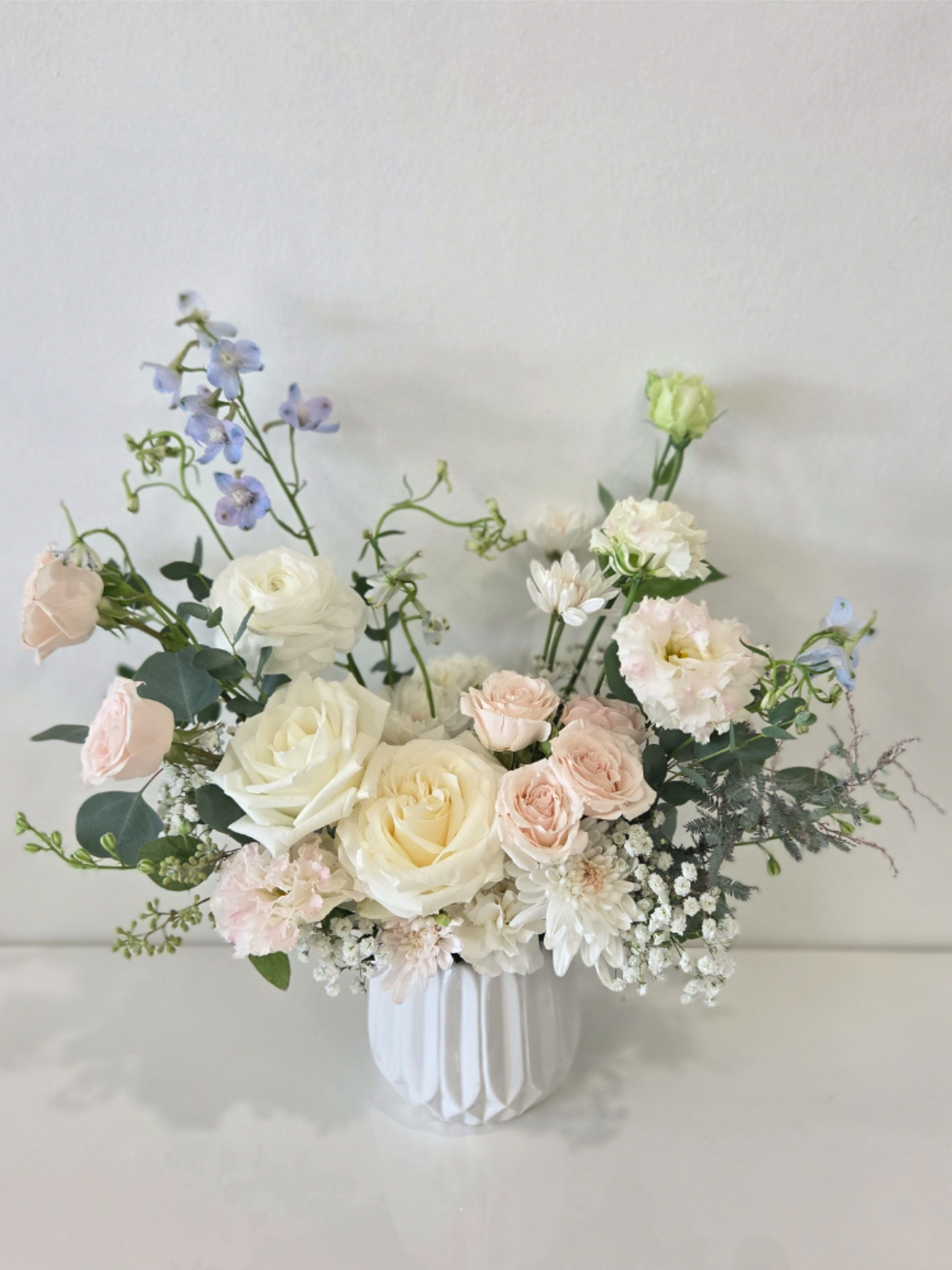 Pastel bouquet of roses and mixed blooms in a white vase