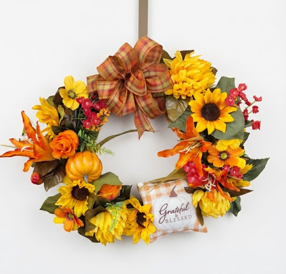 Fall wreath with sunflowers, orange flowers, a plaid bow, and a "Grateful &amp; Blessed" pillow