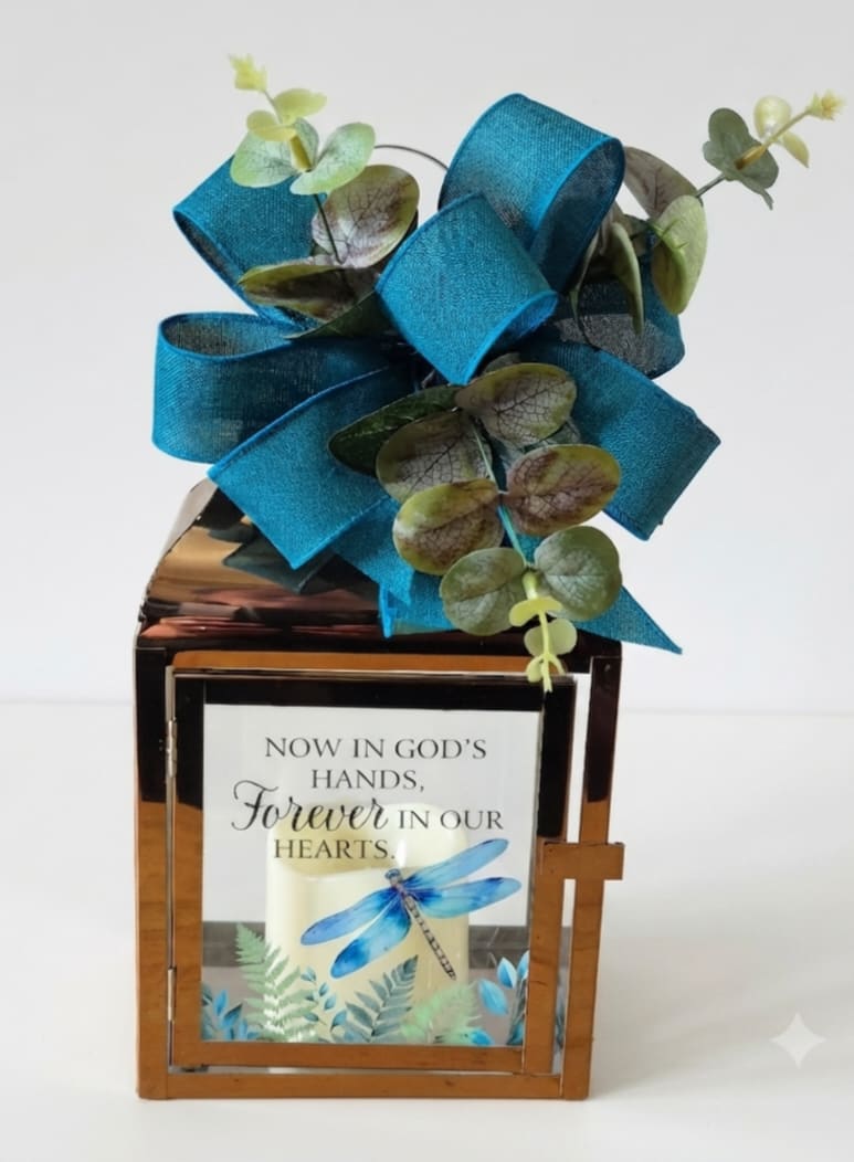 Memorial lantern with a blue ribbon bow and a candle inside