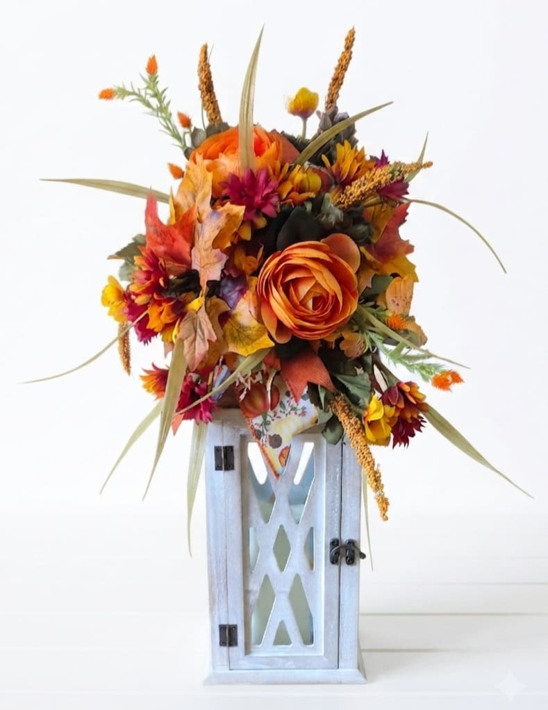 Autumn floral arrangement with orange blooms in a white lantern