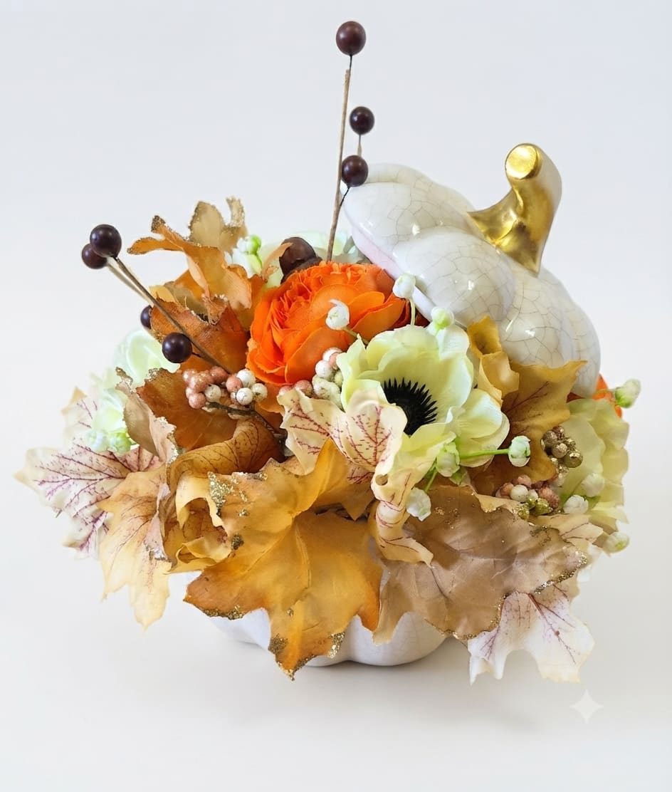 Orange and cream floral arrangement in a white pumpkin container
