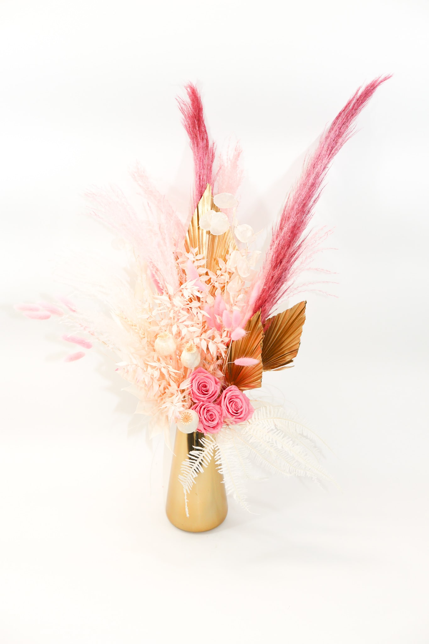 Pink roses and dried pampas-style stems in a gold vase