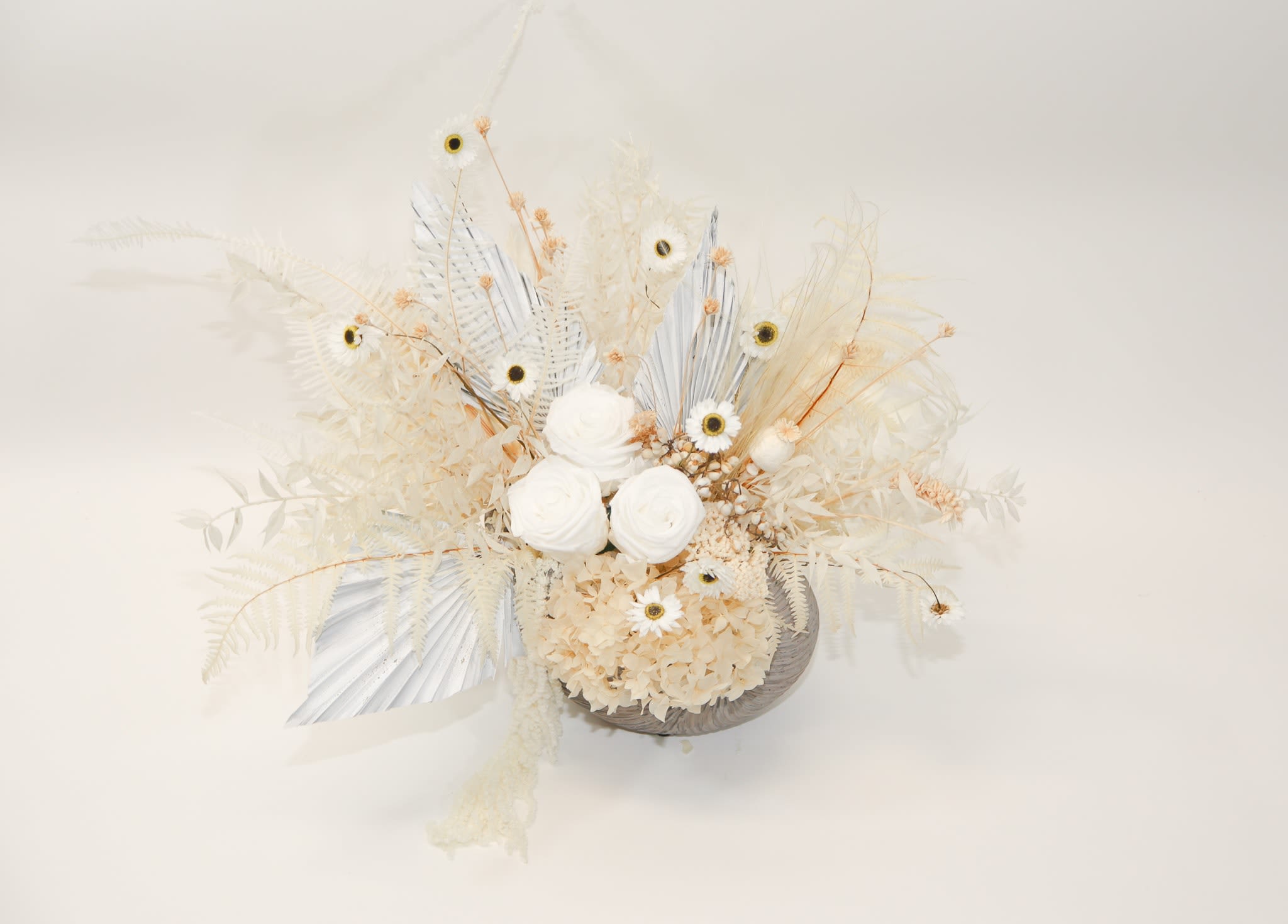 Cream-colored floral arrangement with white blooms and dried accents