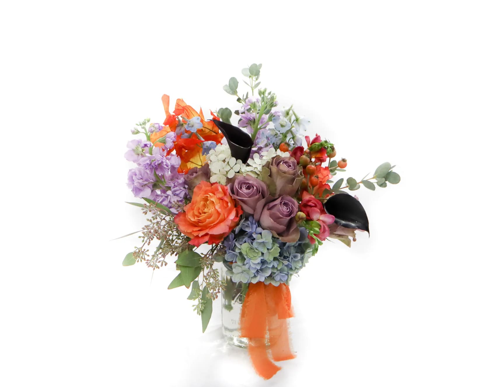 Colorful bouquet of roses, hydrangeas, and mixed blooms in a glass vase