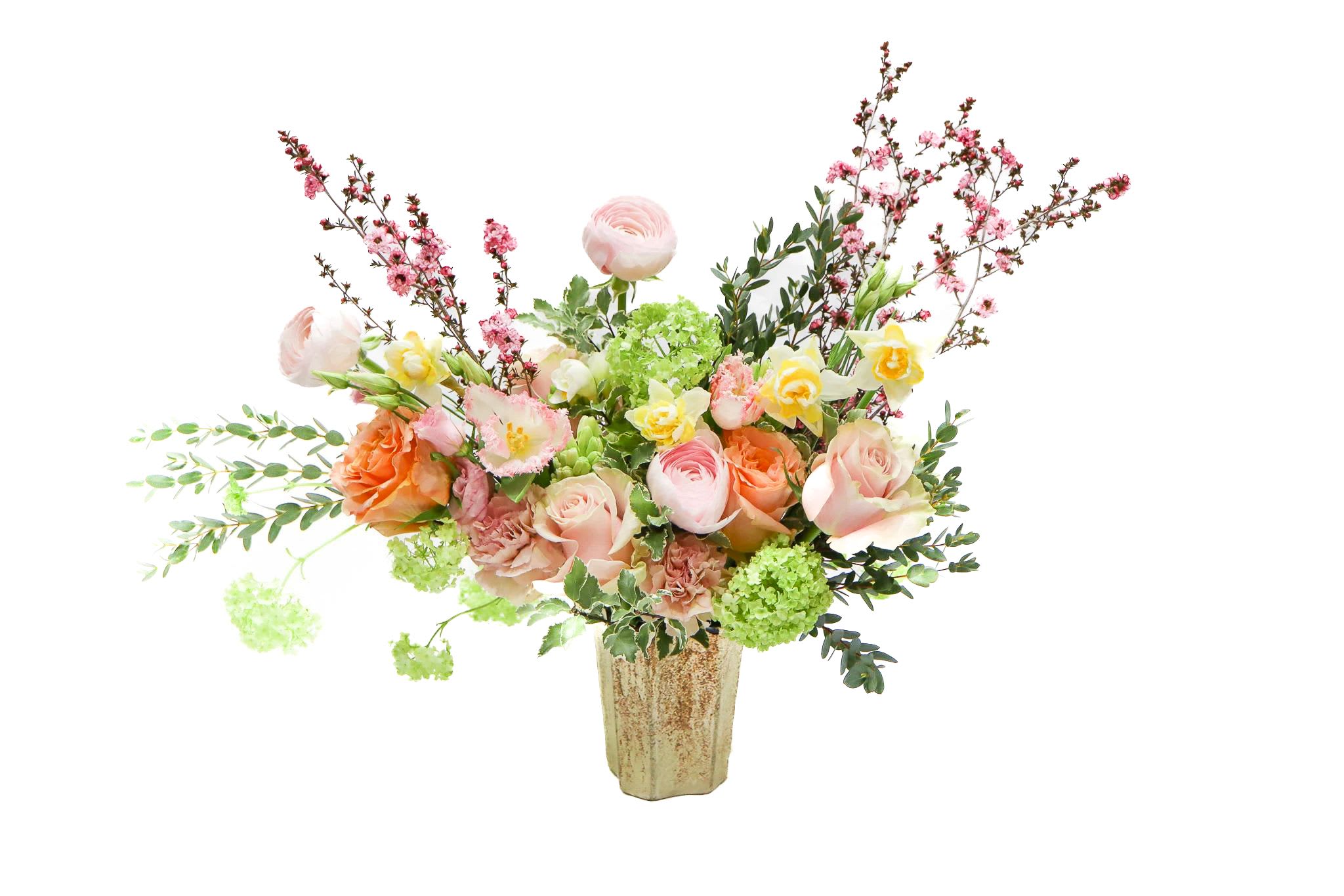 The Pastel - Garden Celebration Floral Arrangement  Bright, cheerful, and beautifully expressive, this garden-inspired arrangement is a true statement of joy. Featuring soft blush and peach roses, delicate ranunculus, sunny yellow blooms, and lush green hydrangea, it’s artfully accented with flowering branches and fresh foliage for a natural, airy look.  Arranged in a rustic yet elegant ceramic vase, this design feels like freshly gathered blooms from a countryside garden—full of movement, texture, and life. It’s perfect for celebrating milestones, sending congratulations, or bringing warmth and happiness into any space.  Why customers love this arrangement:  A vibrant mix of blush, peach, yellow, and green tones  Premium garden-style blooms with natural movement  Designed in a stylish decorative vase  Ideal for celebrations, housewarmings, birthdays, or thank-you gifts  This arrangement makes a bold yet graceful impression, filling the room with color, charm, and uplifting beauty. Joyful, fresh, and designed to be remembered. 
