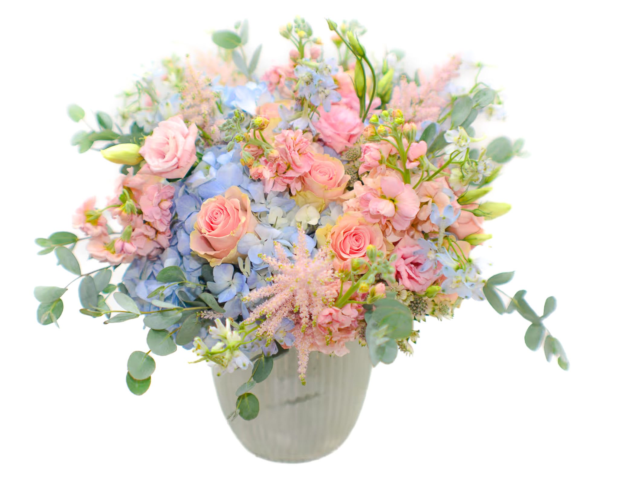 The Unicorn  - A stunning combination of colors, sweet and lovely. This jewel-toned bouquet includes some of our most loved flowers. Soft pink roses, peach matthiola, pink astilbe, baby blue hydrangea and blue delphinium.   A blue flower, it stands for desire, love, and the metaphysical striving for the infinite and unreachable. It symbolizes hope and the beauty of things. Comes in a glass white vase. 