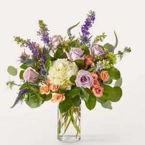 Lavender roses and purple flowers in a clear glass vase