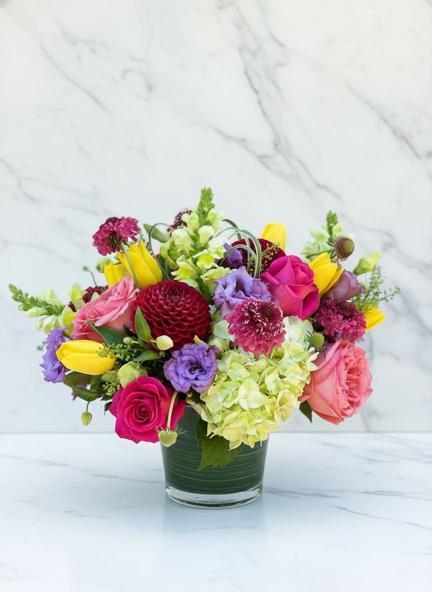 Summer Jubilee - A vibrant summer arrangement featuring hot pink roses, burgundy dahlia, yellow tulips, lavender lisianthus, hydrangea, and seasonal garden blooms. Designed in a modern glass cylinder vase, Summer Jubilee brings cheerful color and fresh-from-the-garden charm to birthdays, celebrations, and everyday occasions. Perfect for flower delivery in San Francisco.