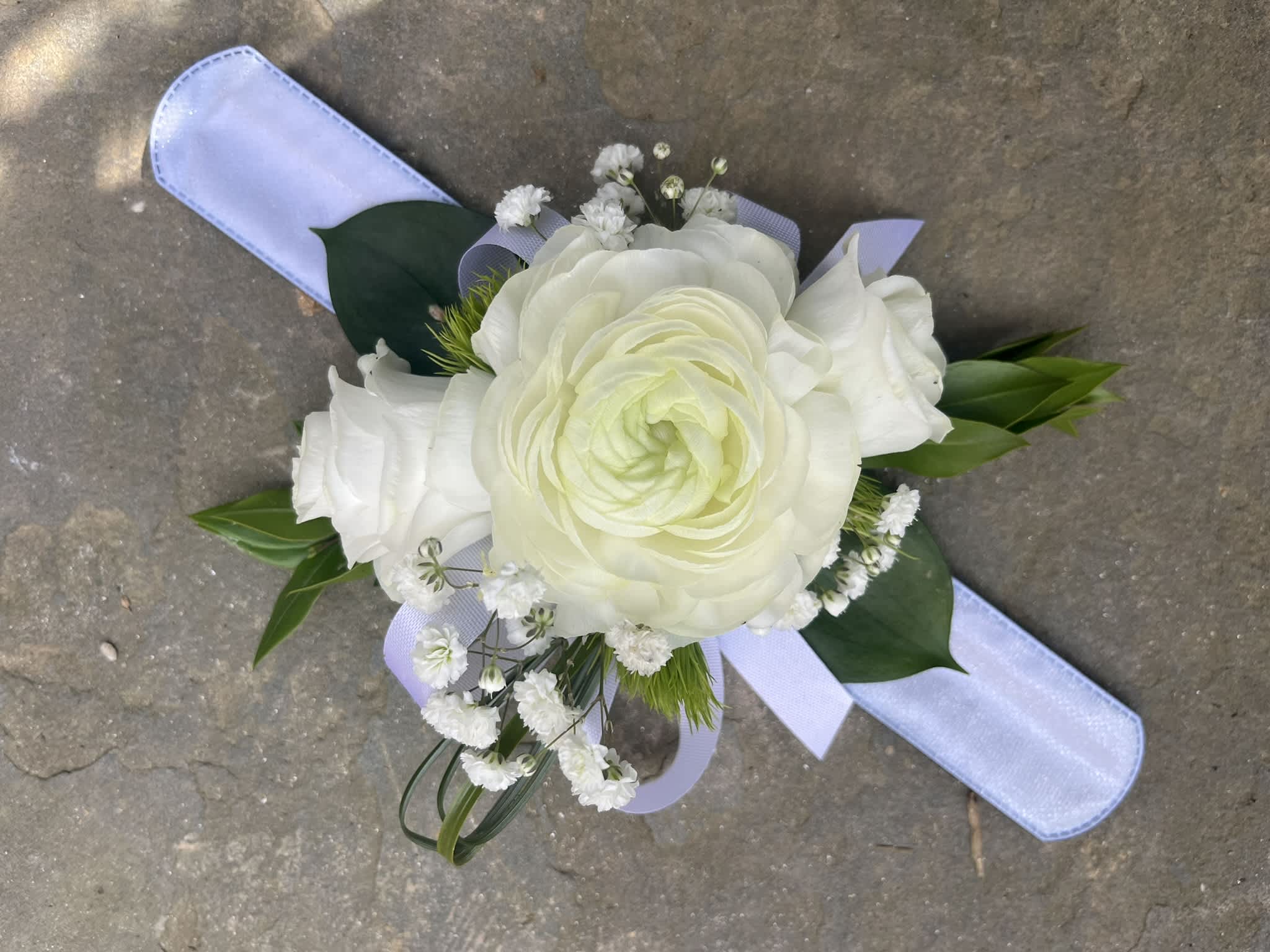 All White Corsage - A small arrangement of beautiful flowers and greens secured to a snap bracelet with a ribbon to tie around the bracelet.  I always add fun touches of unique flowers or greens along with the main flowers.  I love adding some sparkle and bedazzling on flowers, ribbons, and now friendship bracelet sayings.  You can choose to add a word or phrase or not to a corsage as a fun beautiful homecoming or prom accessory.  