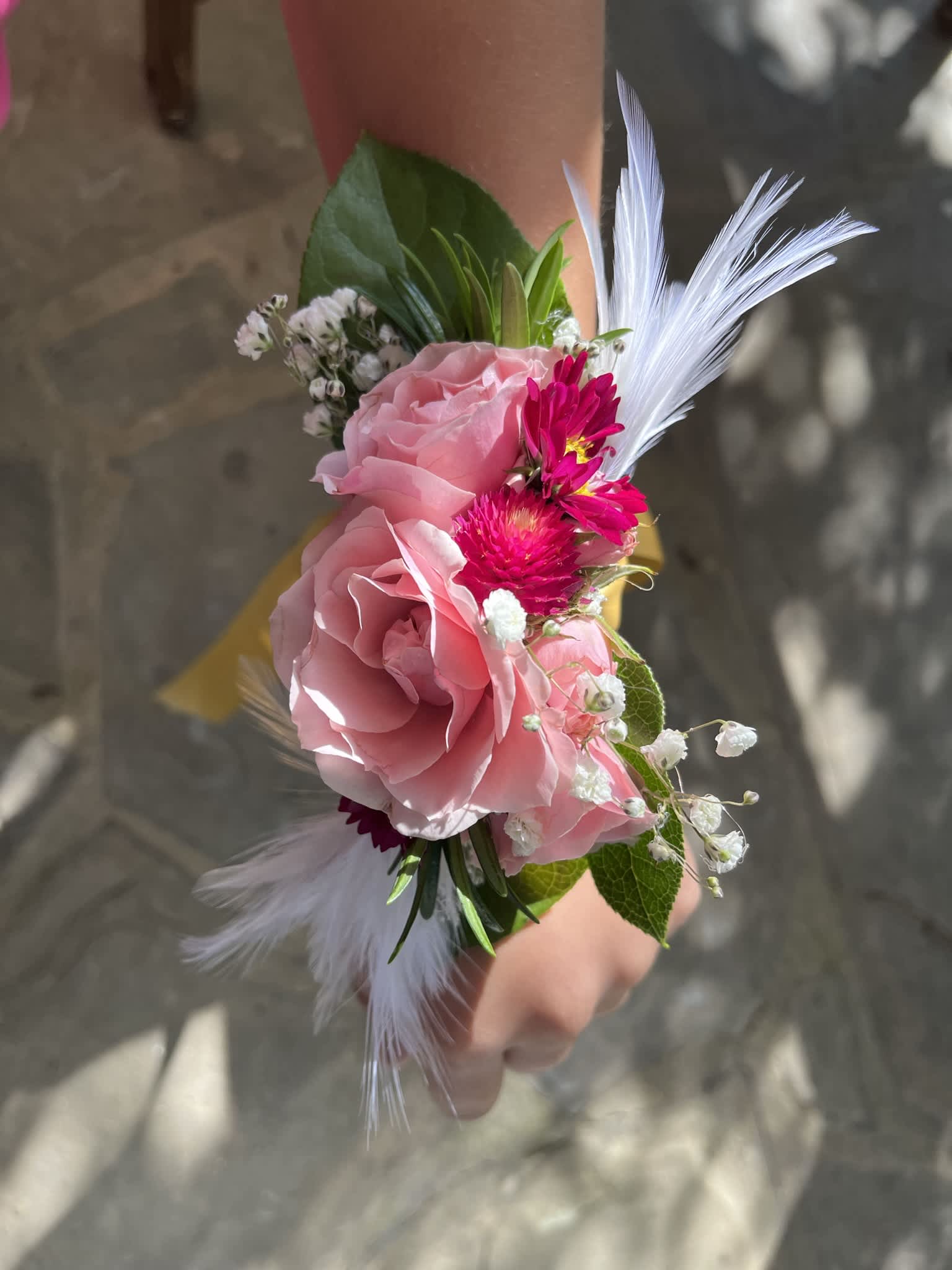 Pink Corsage - A small arrangement of beautiful flowers and greens secured to a snap bracelet.  I always add fun touches of unique flowers or greens along with the main flowers.  I love adding some sparkle and bedazzling on flowers, ribbons, and now friendship bracelet sayings.  You can choose to add a word or phrase or not to a corsage as a fun beautiful homecoming or prom accessory.  