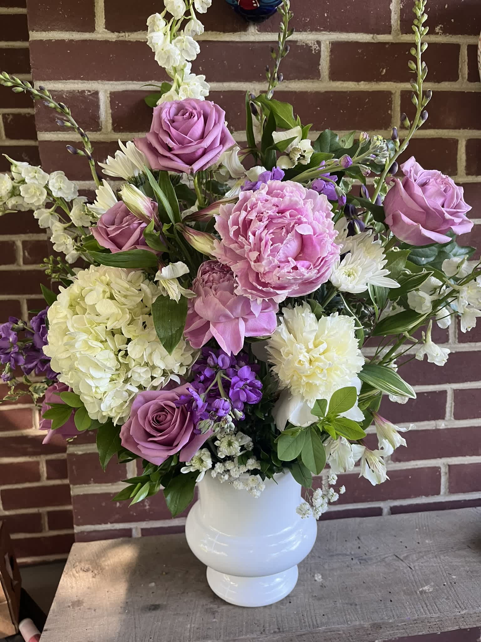 Pink roses and peonies in a white vase with white and purple flowers