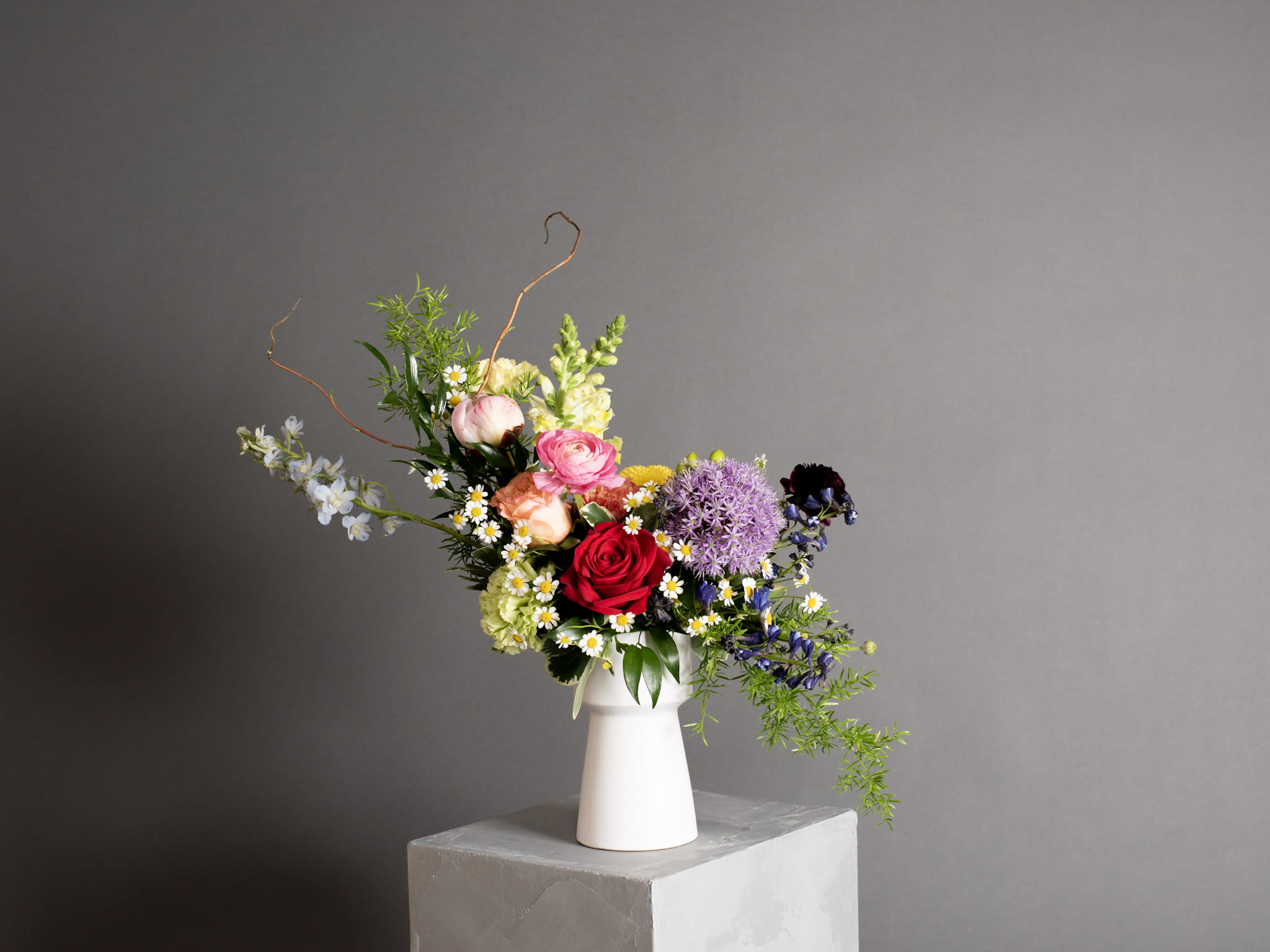 Mixed bouquet in a white vase with roses and purple blooms