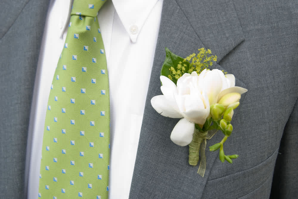 White boutonniere pinned to a gray suit jacket
