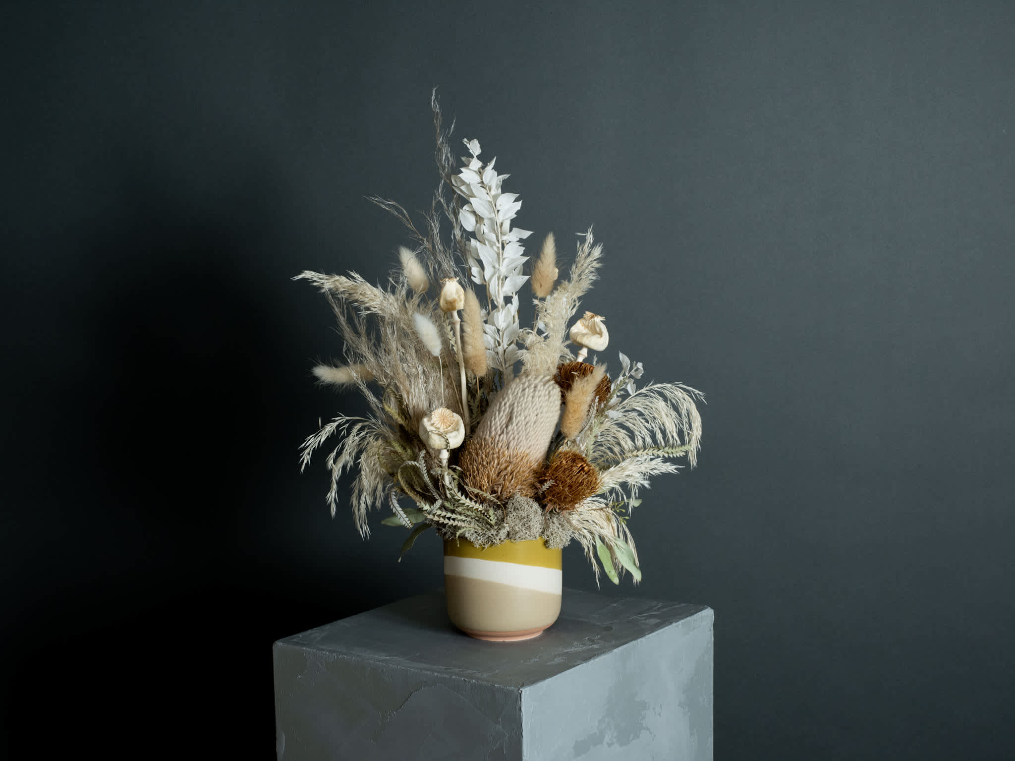 Dried floral arrangement in a striped ceramic vase