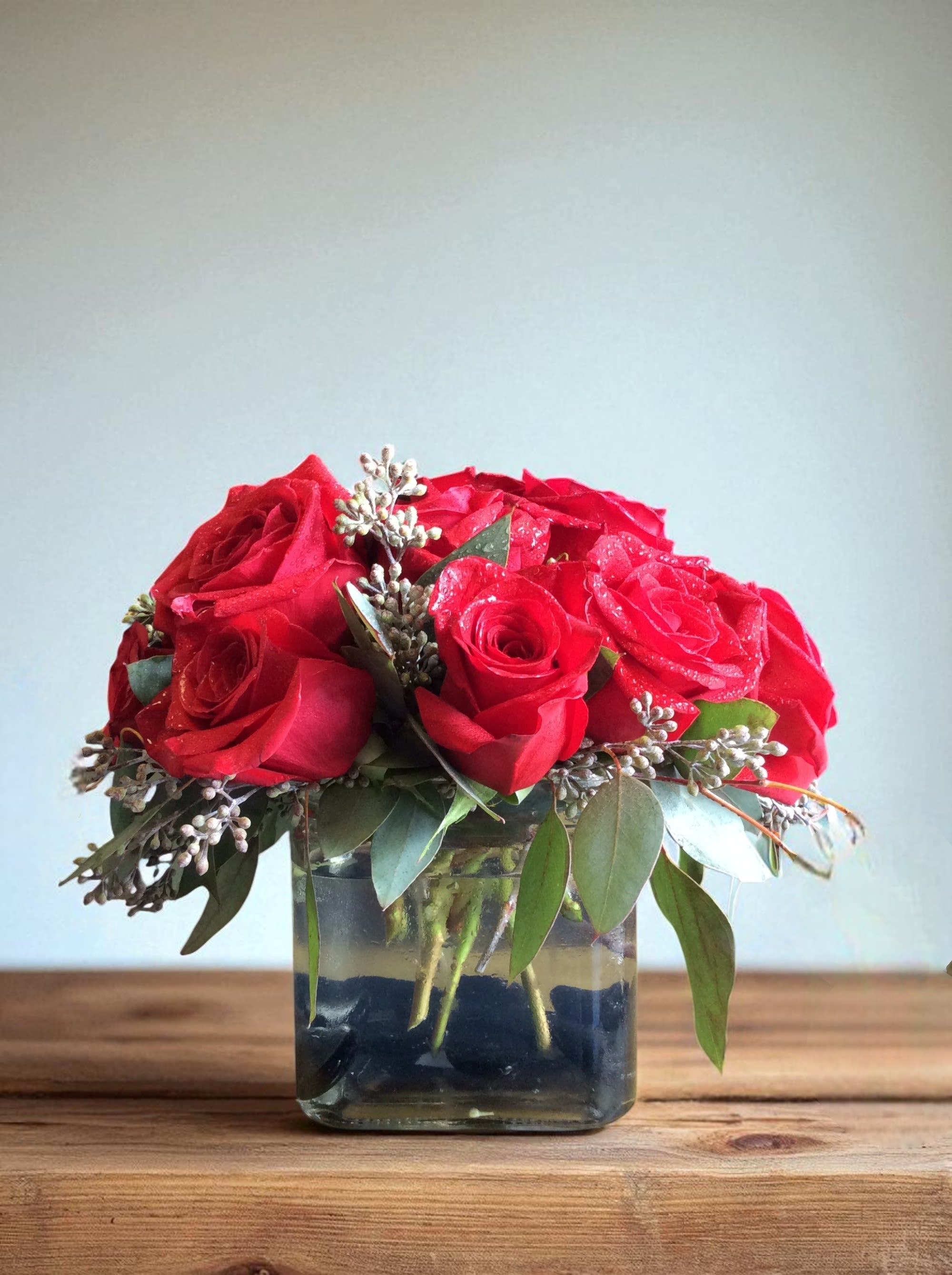 Red roses arranged in a square glass vase