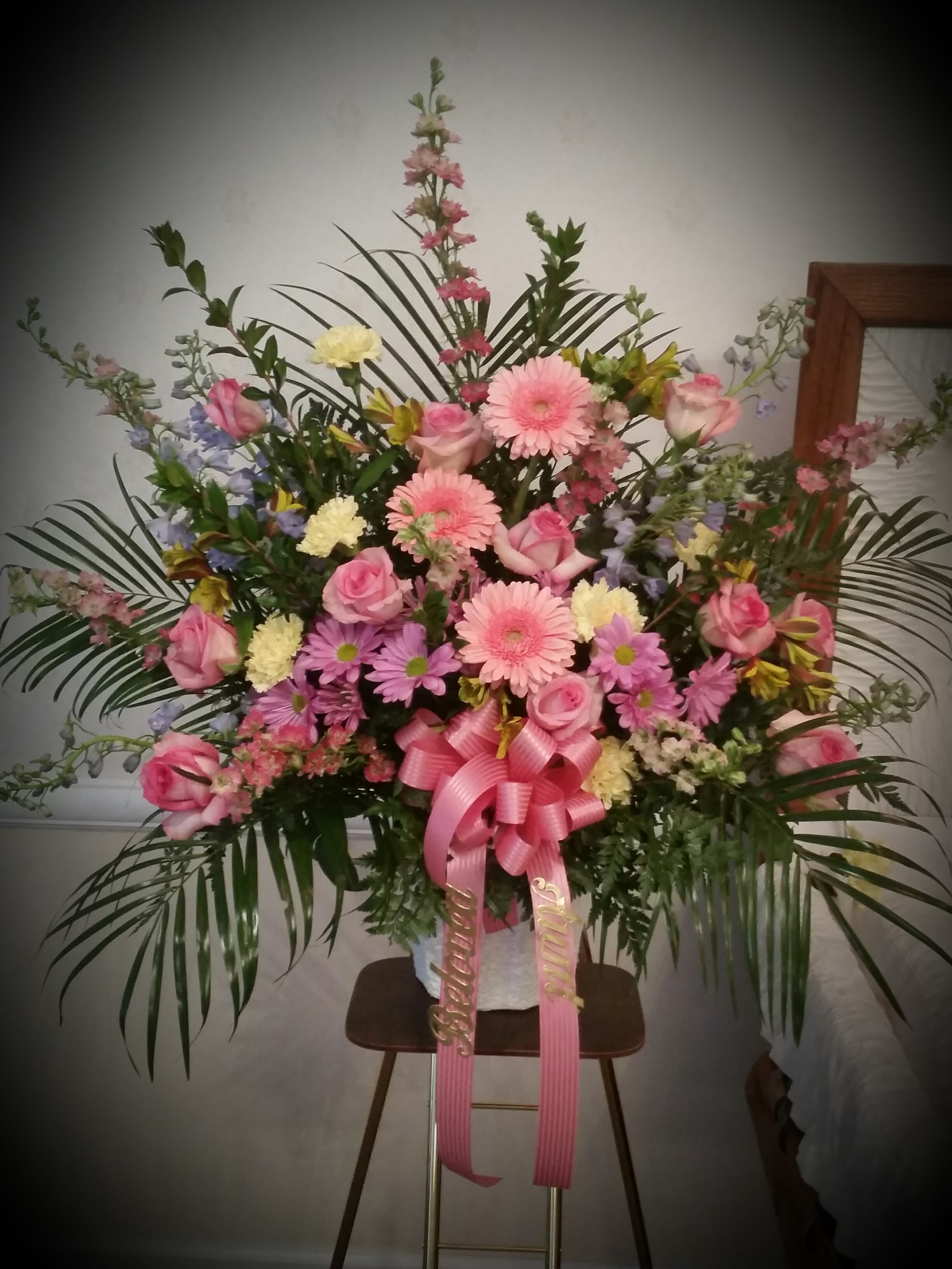 Large pink and purple floral standing arrangement with a ribbon bow
